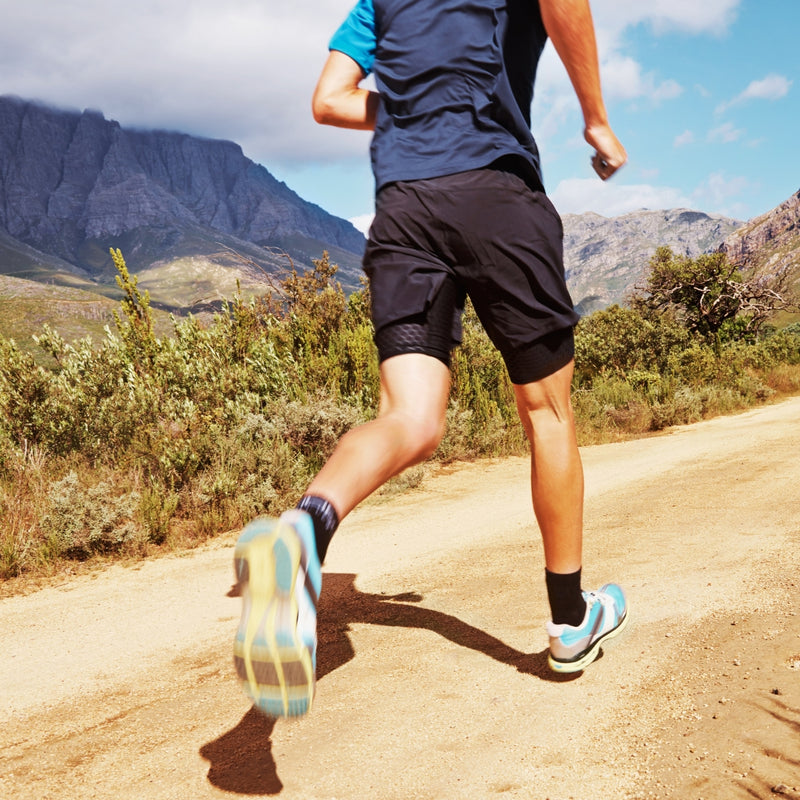 Person running on a trail with mountains in the background