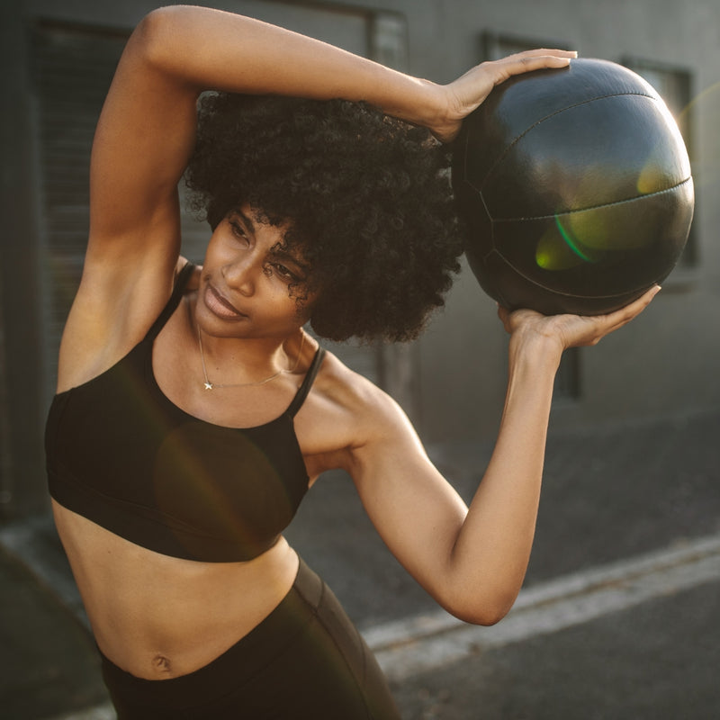 Woman holding a medicine ball in an urban setting