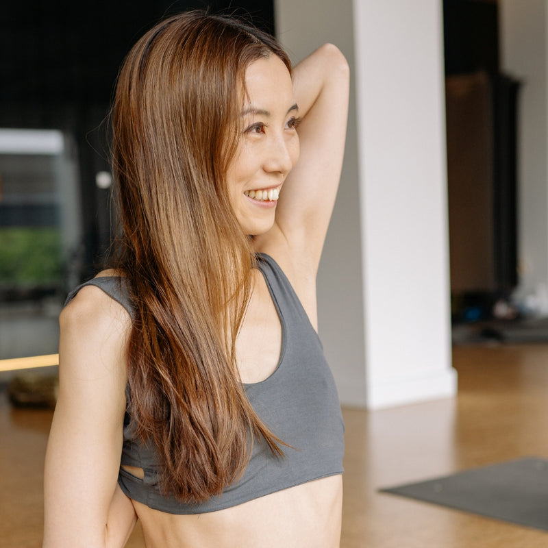 Woman in a gray sports bra and shorts smiling in a home setting